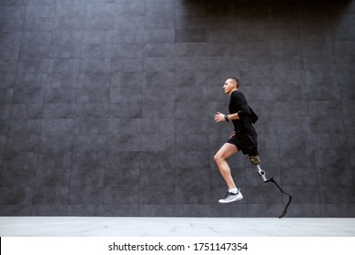 Side View Of Handsome Fit Caucasian Sportsman With Artificial Leg Running Outside.