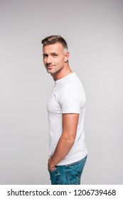 Side View Of Handsome Man In White T-shirt Smiling At Camera Isolated On Grey