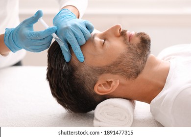 Side view of handsome middle aged man getting hair treatment at beauty salon. Man having mesotherapy session at aesthetic clinic, therapist hands in gloves making injection in scalp, closeup - Shutterstock ID 1891477315