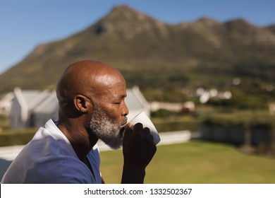 Side View Of A Handsome Senior African American Man Drinking A Cup Of Coffee On The Balcony At Home