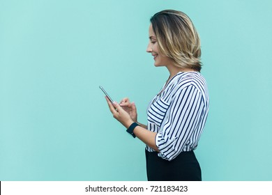 Side view of happiness business woman, punished alone at blue wall and using smartphone. Indoor studio shoot - Powered by Shutterstock