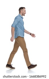 Side View Of Happy Casual Man Laughing And Wearing Blue Shirt, Stepping On White Studio Background