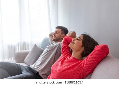 Side View Of A Happy Couple Breathing And Resting Lying In A Couch At Home With A Window In The Background. Couple At Home Relaxing In Sofa.