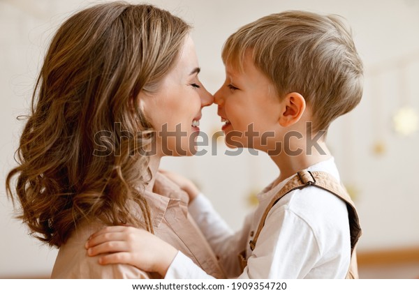 Side view of happy family: young woman\
and little boy in casual clothes embracing   while congratulating\
on holiday mothers day in sunny room at\
home 