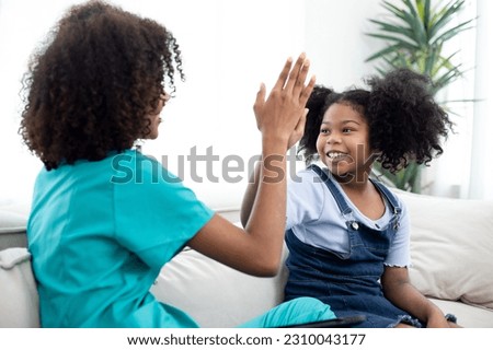 Side view happy little preschool girl giving high five to male doctor at meeting at home. Smiling small patient celebrating successful treatment. Home health care.