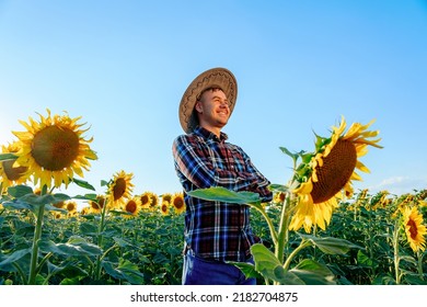 side view of Happy lucky young farmer with arms crossed stands in his field with sunflowers. Man smiles happy, it is a good sunny day. On the head is a hat, it protects from the scorching sun. - Shutterstock ID 2182704875