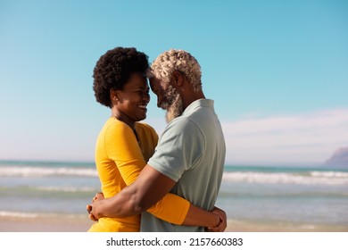 Side view of happy romantic african american couple embracing and dancing against sea and blue sky.  - Powered by Shutterstock