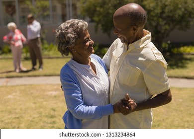 Side view of happy senior couple dancing together on sunny day in garden