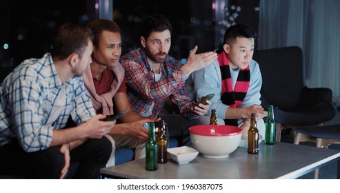 Side View Of Happy Successful Multi-ethnic Friends Celebrating Football Victory Game Watching On TV Doing High-five Together.