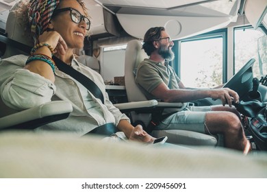 Side view of happy traveler couple inside camper van rv vehicle driving and enjoying road trip vacation or of grid vanlife lifestyle. People and transport concept. Man and woman travel on motor home - Powered by Shutterstock