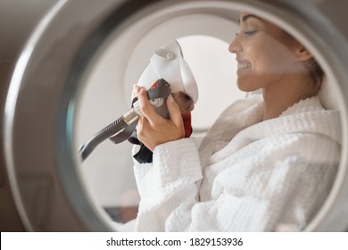 Side view of happy woman receiving oxygen therapy at hyperbaric chamber at health spa.  - Shutterstock ID 1829153936
