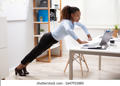 Side View Of A Happy Young Businesswoman Doing Push Up At Workplace - Powered by Shutterstock