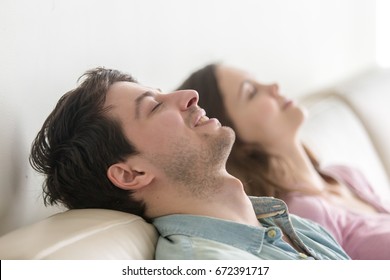 Side View Of Happy Young Couple Enjoying Lying On Sofa At Home, Relaxing With Eyes Closed, Recreating, Dreaming Of Vacation, Meditating And Resting, Listening To Music, Imagining, Leisure Lazy Day