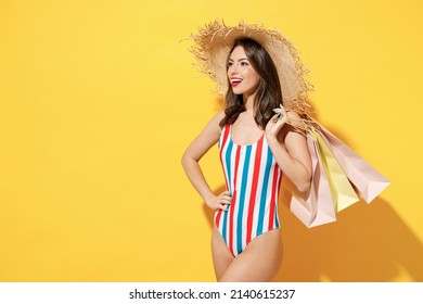 Side View Happy Young Sexy Woman Slim Body Wear Red Blue Swimsuit Straw Hat Hold Package Bags After Shopping Isolated On Vivid Yellow Color Background Studio Summer Hotel Pool Sea Rest Sun Tan Concept
