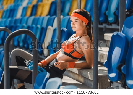 side view of happy young woman relaxing on stairs at sports stadium