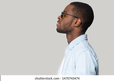 Side view head shot close up young happy african american man in eyeglasses relaxing with closed eyes, deeply breathing, resting, meditating, visualizing future, isolated on grey studio background.