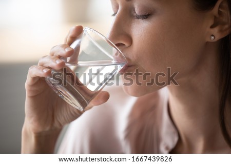 Side view head shot close up young woman drinking pure still water in morning. Healthy thirsty lady enjoying healthy lifestyle daily habit, natural beauty, perfect skin body care aqua balance concept.