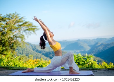 Side view of healthy women practicing yoga. standing in Warrior I pose.asana Anjaneyasana - low crescent lunge pose. in surya namaskar. beautiful landscape view sky on morning.