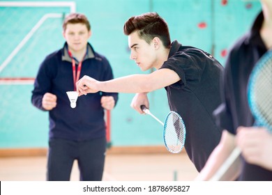 Vista lateral de un chico de secundaria jugando a bádminton durante una clase de gimnasia. Foto de stock