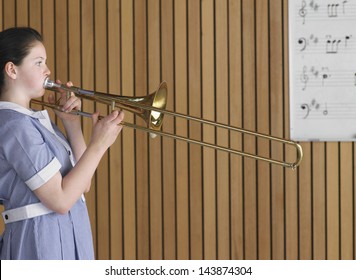 Side View Of High School Girl Playing Trombone In Music Class