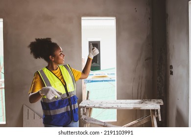 Side view Highly skilled African American female worker plastered the walls of a housing estate at the construction site looking at the work with pride thumbs up for success. - Powered by Shutterstock