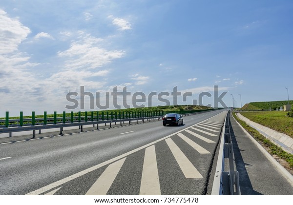 Side view highway on sunny summer day\
crossing vineyards in Romania near Murfatlar. Car rides on highway\
that runs through the vineyards. Highway\
traffic.
