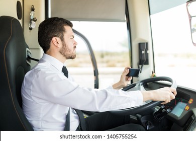 Side View Of Hispanic Bus Driver With Mobile Phone Driving With GPS Navigator