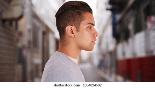 Side View Of Hispanic Man With Cool Undercut Standing In Alley In City