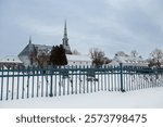 Side view of historical 1873 church and facade of the oldest remaining North American presbytery, built in 1739, seen in winter, Saint-Michel-de-Bellechasse, Quebec, Canada