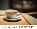 Side view of hot latte coffee with latte art in a white cup on wooden table