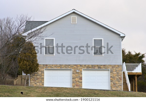 Side view of a house, with windows, two\
door garage, and deck. Blue vinyl\
siding.