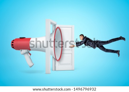 Side view of huge megaphone in open doorway knocking businessman off his feet with soundwave and making him grab at door so as not to fly away. Speak Up Policy. Breaking news. Social media.