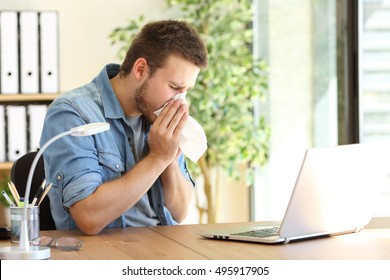 Side view of an ill entrepreneur sneezing in a wipe at office near a window - Powered by Shutterstock