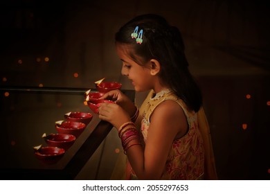 Side view of an Indian Girl arranging Diyas during Diwali festival