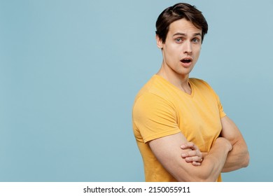 Side view indignant young man 20s wear yellow blank print design t-shirt hold hands crossed folded look camera isolated on plain pastel light blue background studio portrait. People lifestyle concept