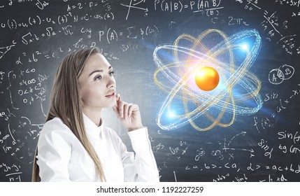 Side view of inspired young woman with long fair hair wearing white shirt thinking about challenging scientific problem. Atom hologram and blackboard with formulae. Double exposure