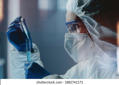 Side View Of Laboratory Technician Wearing Safety Goggles And Mask And Pipetting Out Chemical Mixture To Test Tube. Clinical Researcher Developing Effective Anti-coronavirus Vaccine Or Treatment