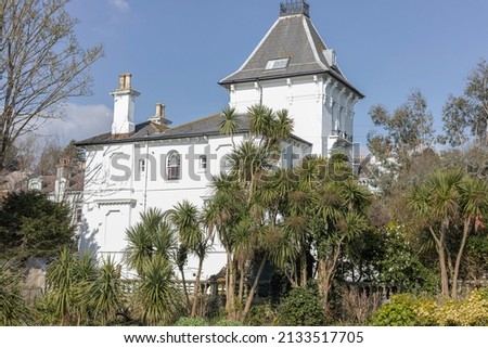 Side view of a large white house with yukka plants and blue sky 