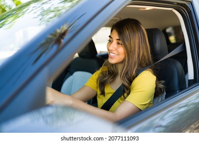 Side view of a latin woman with the seatbelt on feeling happy while driving her car  - Powered by Shutterstock