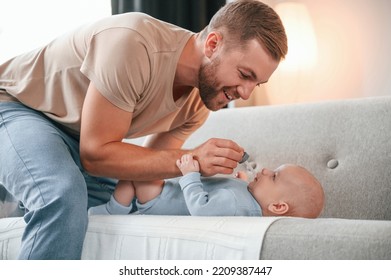 Side View. Laying Down On The Sofa. Father With His Newborn Baby Is Indoors. Conception Of Single Dad.