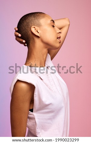 Side view of a liberated female with hand on head and eye closed. Bald woman standing against colorful background.