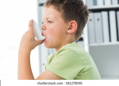 Side view of little boy using an asthma inhaler in clinic - Powered by Shutterstock