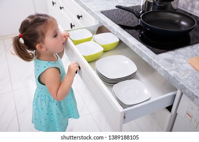 Side View Of Little Girl Open The Kitchen Drawer
