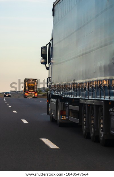 Side view of loaded European\
truck in motion on asphalt road, transportation and delivery\
concept. Detail on delivery truck. Bucharest, Romania,\
2020