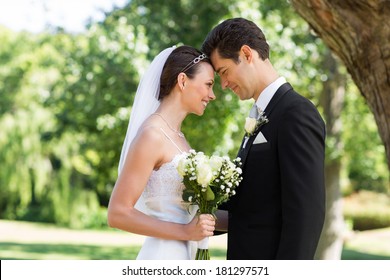 Side view of loving newly wed couple with head to head standing in garden - Powered by Shutterstock