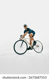 Side view low angle image of focused man, professional cyclist in full gear, riding bike, training isolated on white background. Concept of sport, competition, active lifestyle, endurance