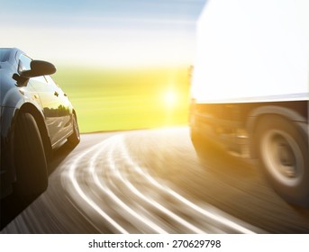 Side View Of A Luxury Car Driving Fast On A Winding Road In The Woods