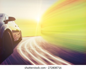 Side View Of A Luxury Car Driving Fast On A Winding Road In The Woods