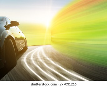 Side View Of A Luxury Car Driving Fast On A Winding Road In The Woods