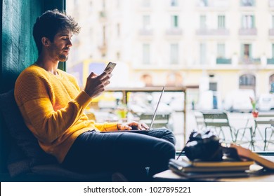 Side view of male blogger browsing profile in networks on smartphone via 4G internet connection resting in stylish coffee shop with modern laptop computer.Young man chatting online on mobile phone - Powered by Shutterstock